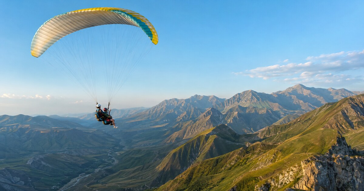 Оригинальная обложка GeoTrips: тандемный параплан над горным ландшафтом